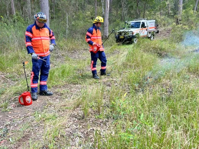 Crew preparing drip torches beside a Striker at the edge of a burn