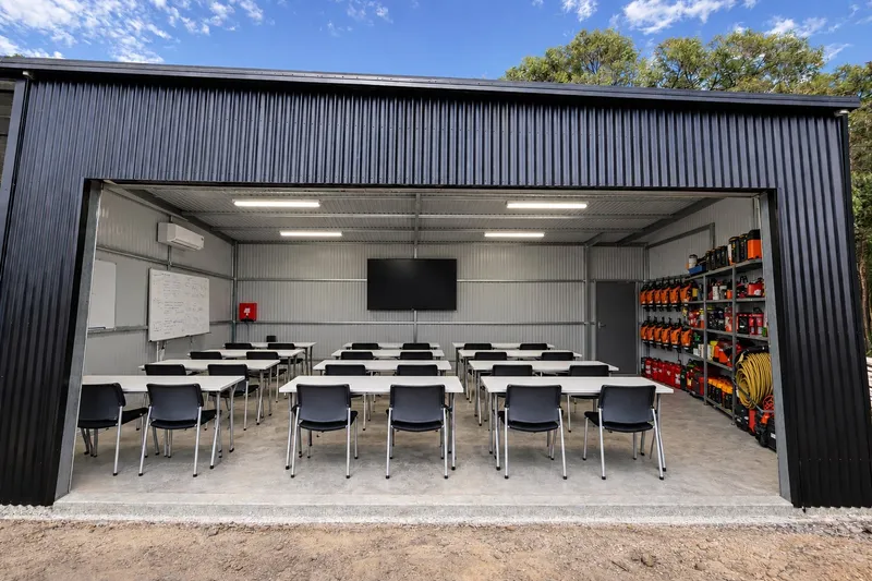 The 25-seat training room, open to the yard, with a screen and whiteboard at the far end and equipment racking along one wall