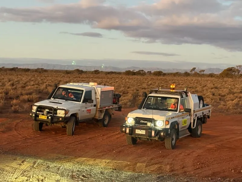 Response vehicles on a remote desert track at dusk